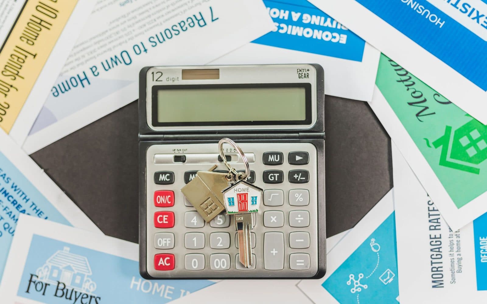 Una calculadora y una maqueta de casa sobre un escritorio representando cálculos de oferta